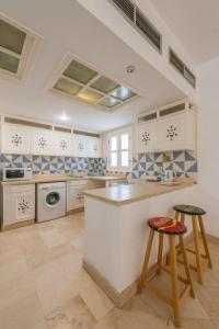 a large kitchen with white cabinets and two stools at Abutig Marina flat ground floor in Hurghada
