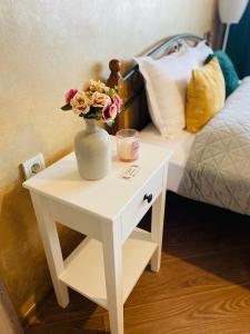 un tavolo bianco con un vaso con dei fiori sopra di PANORAMA-М a Vratsa