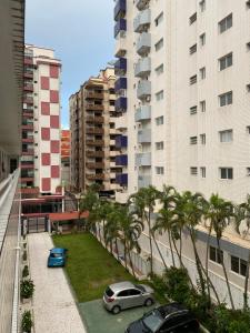 a parking lot with palm trees and cars in a city at Canto do Forte experience in Praia Grande
