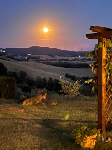 una puesta de sol sobre un campo con la luna en el cielo en Agriturismo Casallario, en Volterra