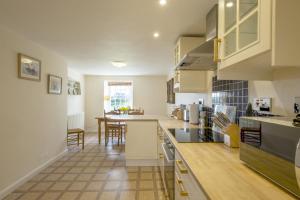 a large kitchen with white cabinets and a table at White Lodge Haughton Castle 2 in Hexham