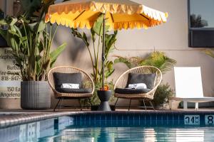 two chairs and an umbrella next to a swimming pool at Hotel Burbank in Burbank