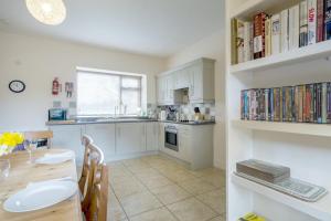 une cuisine avec des armoires blanches et une table avec des chaises dans l'établissement Garden Cottage Haughton Castle, à Hexham 7 autres photos