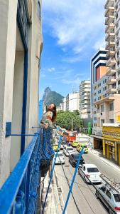 uma mulher de pé na varanda de um edifício em HMG Rio Suítes no Rio de Janeiro