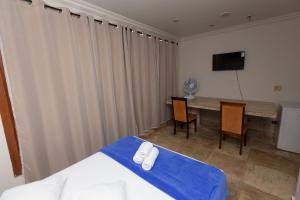 a room with a bed and a table and a television at Pousada Wafeh Pampulha Suítes in Belo Horizonte