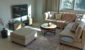 a living room with a couch and a tv at Downtown Oasis, Burj Khalifa Views, Luxury Amenities in Dubai