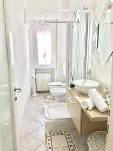 Casa di Riccardo في سافونا: حمام ابيض مع مغسلتين ودورتين مياه