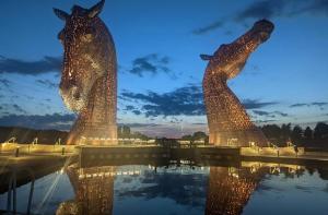 two statues of horses standing in the water at night at Caledonia House in Rosyth