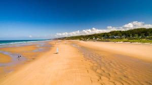 a view of a beach with a surfboard in the sand at Maison rénovée cour fermée et terrasse 800 m plage Omaha beach avec table de ping pong proche Port en Bessin in Vierville-sur-Mer