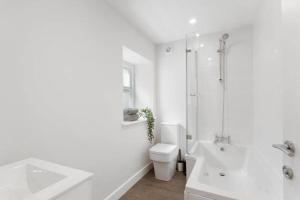 a white bathroom with a toilet and a shower at The Donkey Shed with Hot tub in Kent