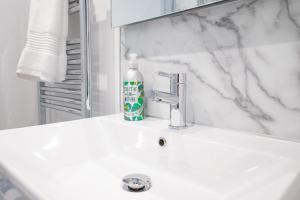 a white bathroom sink with a bottle of soap on it at The Links Suites in Newcastle