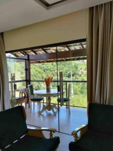 - un salon avec une table, des chaises et une grande fenêtre dans l'établissement Casa dos Colibris, Lugar memorável!, à Chã Grande