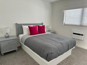 a bedroom with a large bed with two red pillows at EBBTIDE INN in St. Pete Beach