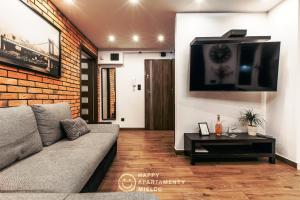 sala de estar con sofá y TV de pantalla plana en Happy - Happy Apartamenty Mielec, en Mielec