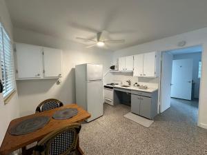 a kitchen with a table and a white refrigerator at EBBTIDE INN in St Pete Beach