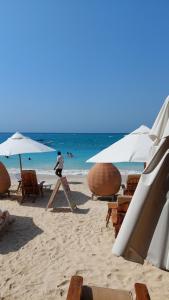 a beach with chairs and umbrellas and the ocean at Hotel Calamari Baru in Playa Blanca