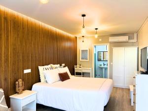 una camera con un letto bianco e una parete in legno di Costa Brava Alojamento a Benedita