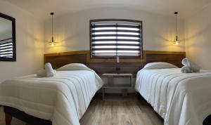 a bedroom with two beds with white sheets and a window at Residencial Victoria Said in Linares