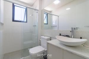 uma casa de banho branca com um lavatório e um chuveiro em Belo Estudio com design moderno CNT303 em Florianópolis