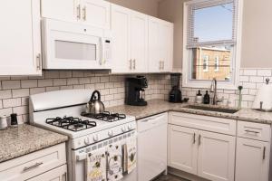 a white kitchen with a stove and a microwave at Peaceful Cozy Townhouse in Baltimore