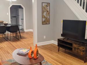 a living room with a television and a table with vases at Peaceful Cozy Townhouse in Baltimore