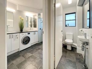 a white bathroom with a washing machine and a sink at Foreshore Paradise Nelson Bay in Nelson Bay +34 photos