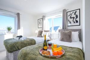 ミルトン・キーンズにあるStunning 4 Bedroom 2 Bathroom House - Close to City Centre - Sleeps 8 - Free Parking, Super-Fast Wifi and Smart TVs by Yoko Propertyのベッド2台(食料品とワイン1本のトレイ付)
