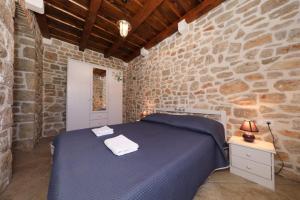1 dormitorio con 1 cama azul en una pared de piedra en House Cirrus, en Sukošan