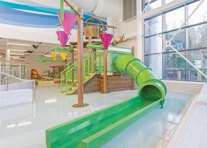 a playground with a green slide in a room at Luke's Lodge in Newton Abbot