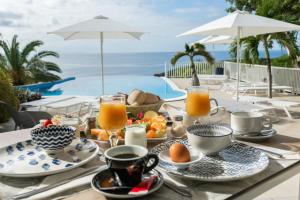 a table with a breakfast of orange juice and fruit at Hôtel Amaudo in Saint-François