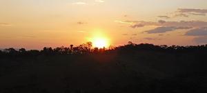 コンセイサオン・ダ・イビティポカにあるIbitiAnJo - Suítesの手前の木々の茂る畑に沈む夕日