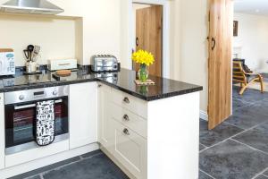 uma cozinha com uma bancada preta e um fogão em Manor Coach House em Farrington Gurney