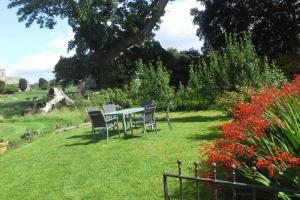 uma mesa e cadeiras num jardim com flores em Manor Coach House em Farrington Gurney