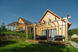 una casa de madera con terraza en el césped en Dolina Narie, en Bogaczewo