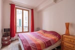 パリにあるLuminous Parisian-style 1BD ApartmentBellevilleのベッドルーム1室(ベッド1台付)、赤いカーテン付きの窓が備わります。