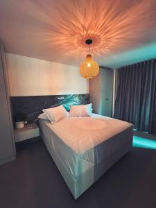 a bedroom with a large bed with a chandelier at Villa Verde Bangalô - Garopaba - SC in Garopaba