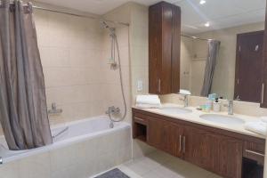 uma casa de banho com 2 lavatórios, uma banheira e um chuveiro em Downtown Oasis, Burj Khalifa Views, Luxury Amenities em Dubai