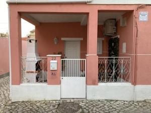 a pink house with a gate and a door at Maria Trafaria House in Trafaria