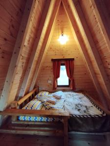 Cama en una cabaña de madera con ventana en Silence House en Šavnik