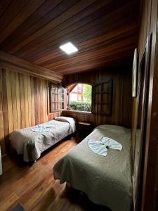 twee bedden in een kamer met houten wanden en houten vloeren bij Pousada da Lua in Campos do Jordão