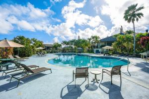 una piscina en un complejo con sillas y mesa en Mauna Kai 8, en Princeville