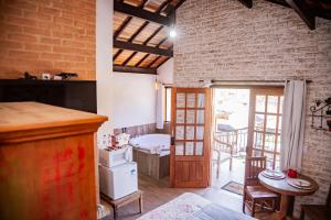 a room with a brick wall and a kitchen with a table at Chalés Cantinho do Sossego in Monte Verde