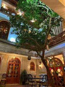 un albero al centro di un edificio con tavoli e sedie di RIAD SHAJARA a Marrakech