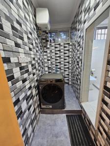 ein Badezimmer mit einer Waschmaschine und einem Trockner an einer Fliesenwand in der Unterkunft Double A apartment in Ngambo
