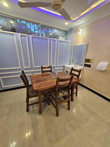 a wooden table and chairs in a room with windows at Double A apartment in Ngambo