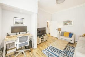 a living room with a desk and a tv and a couch at Striking & Modern 2BD Flat wGarden - East Dulwich in London