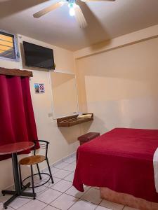 um quarto com uma cama, uma mesa e uma televisão em Hotel Buenos Aires em Durango