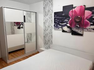 1 dormitorio con una pintura de flores rosas en la pared en Medeea en Zalău