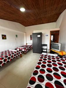 Zimmer mit 4 Betten und einem TV. in der Unterkunft Finca La Toscana in Pereira