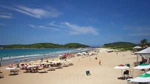 una playa con muchas sombrillas y gente en la playa en Casa em Cabofrio, en Cabo Frío